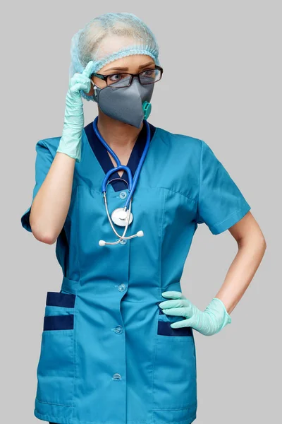 Femme médecin avec stéthoscope portant un masque protecteur et des gants en latex sur fond gris clair — Photo