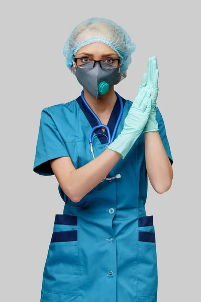 Femme médecin avec stéthoscope portant un masque protecteur et des gants en latex sur fond gris clair — Photo