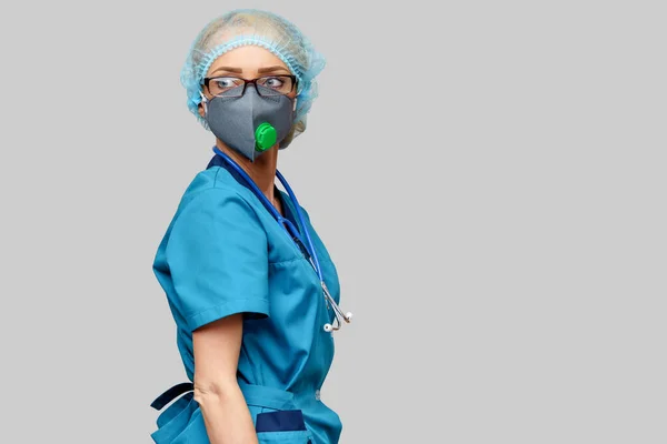 Steteskoplu kadın doktor koruyucu maske takıyor ve açık gri arka plan üzerine lateks eldiven takıyor. — Stok fotoğraf