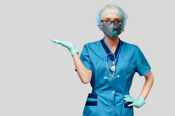 Femme médecin avec stéthoscope portant un masque protecteur et des gants en latex sur fond gris clair — Photo