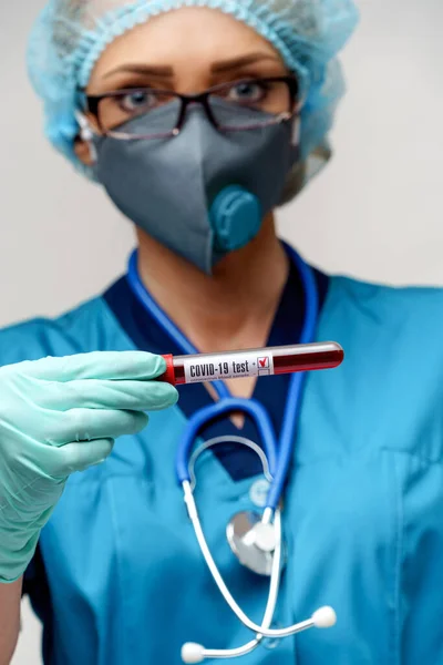 Zdravotní sestra žena v ochranné masce a rukavicích - drží pozitivní koronavirus COVID-19 krevní test — Stock fotografie