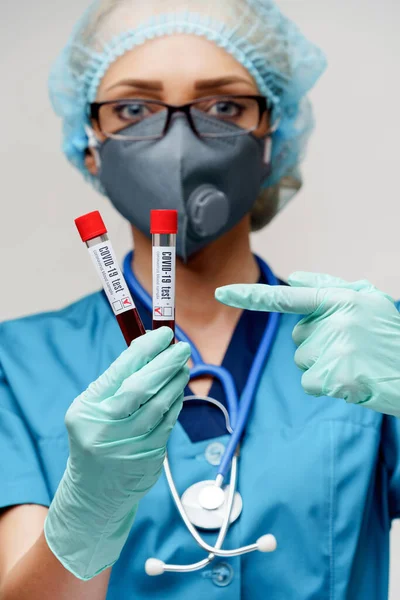 Zdravotní sestra žena v ochranné masce a rukavicích - drží negativní a pozitivní koronavirus COVID-19 krevní test — Stock fotografie