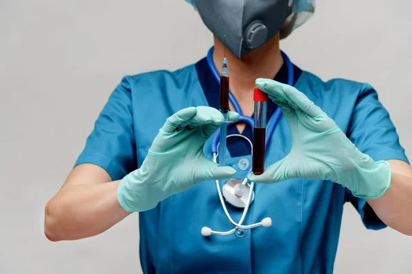 医療看護師の女性は保護マスクと手袋を身に着けています-ウイルスの血液検査管と注射器を保持 — ストック写真