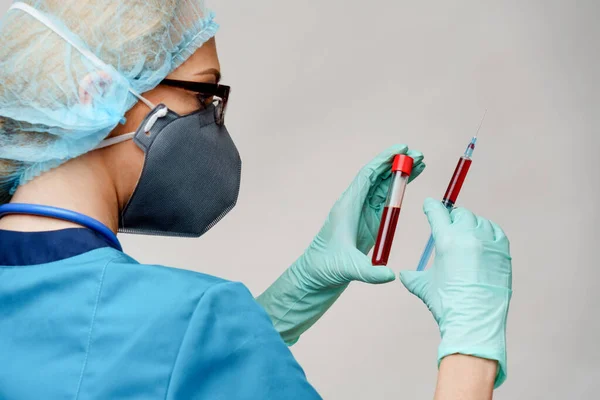 Verpleegkundige vrouw met beschermend masker en handschoenen - met virusreageerbuis en spuit — Stockfoto