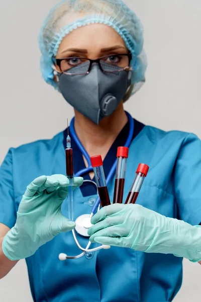 Médico enfermeira mulher usando máscara protetora e luvas - segurando vírus tubo de teste de sangue e seringa — Fotografia de Stock