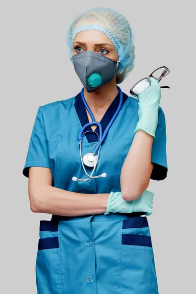 Steteskoplu kadın doktor koruyucu maske takıyor ve açık gri arka plan üzerine lateks eldiven takıyor. — Stok fotoğraf