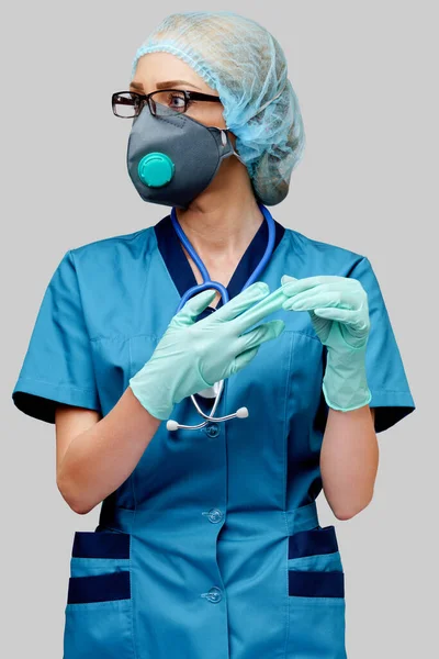 Жінка-лікар зі стетоскопом у захисній масці та латексних рукавичках на світло-сірому фоні — стокове фото