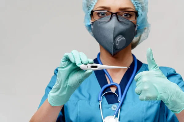 Female doctor with stethoscope wearing protective mask and latex gloves over light grey background holding thermometer — Stock Photo, Image