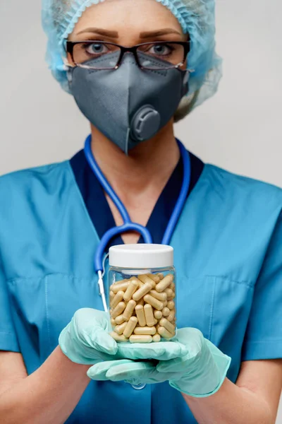 Medico infermiere donna indossando maschera protettiva e guanti di gomma o lattice - tenendo pillole — Foto Stock