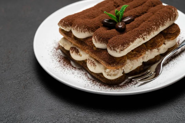 Makanan penutup tiramisu klasik di piring keramik pada latar belakang beton gelap — Stok Foto