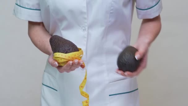 Nutricionista médico conceito de estilo de vida saudável - segurando frutas abacate orgânicos e fita métrica — Vídeo de Stock