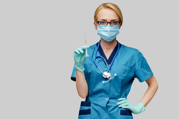 Orvos ápolónő védőmaszkot és kesztyűt viselő nő - a fecskendőt tartja — Stock Fotó