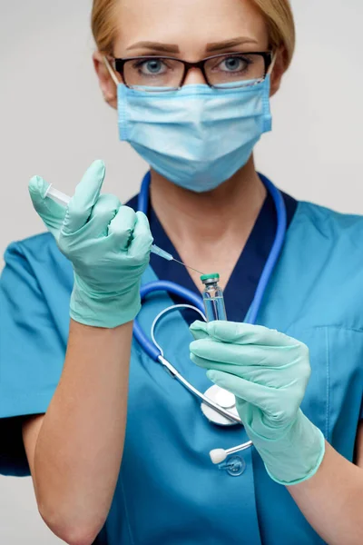 Médico enfermera mujer con máscara protectora y guantes - la celebración de la jeringa — Foto de Stock
