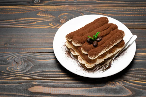 Классический десерт тирамису на керамической пластине на деревянном фоне — стоковое фото