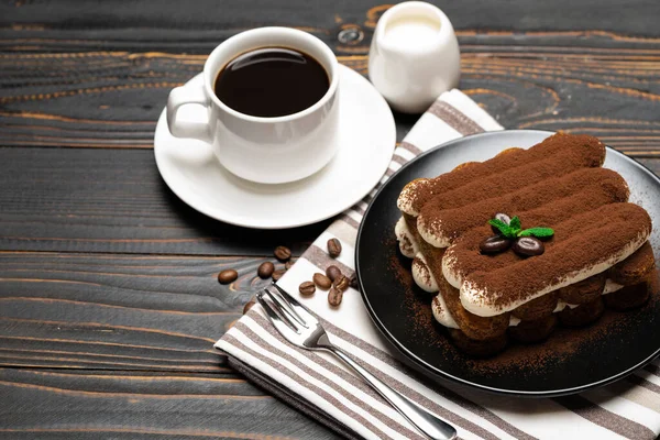 Klassisches Tiramisu-Dessert auf Keramikteller, Milch oder Sahne und Tasse Kaffee auf Holzgrund — Stockfoto