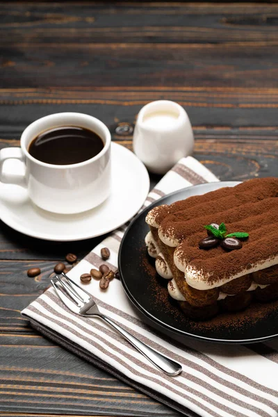Классический десерт тирамису на керамической тарелке, молоке или сливках и чашке кофе на деревянном фоне — стоковое фото