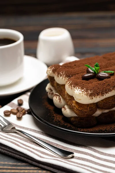 Klassiek tiramisu dessert op keramische plaat, melk of room en kopje koffie op houten ondergrond — Stockfoto