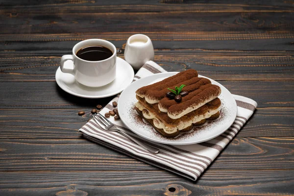 Классический десерт тирамису на керамической тарелке, молоке или сливках и чашке кофе на деревянном фоне — стоковое фото