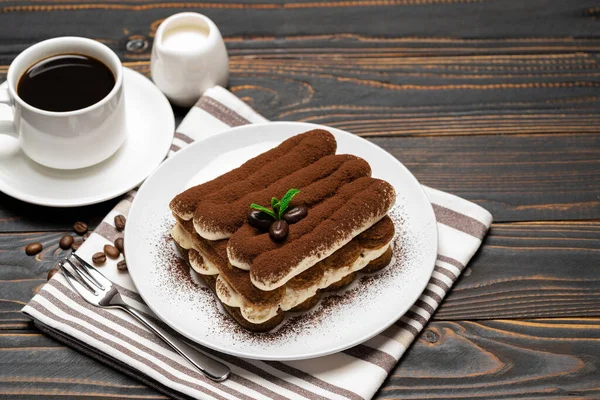 Klassisches Tiramisu-Dessert auf Keramikteller, Milch oder Sahne und Tasse Kaffee auf Holzgrund — Stockfoto