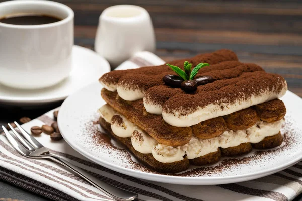 Postre tiramisú clásico en plato de cerámica, leche o crema y taza de café sobre fondo de madera — Foto de Stock