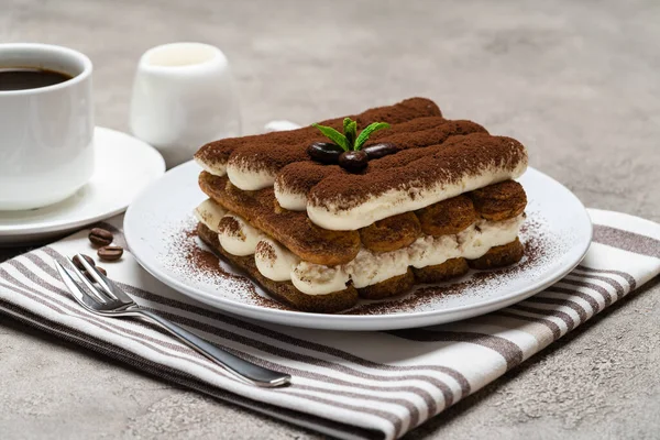 Dessert tiramisu classique sur plaque céramique, lait ou crème et tasse de café sur fond béton — Photo