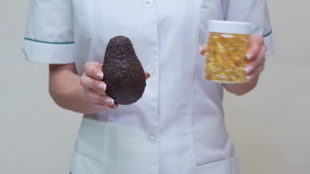 Nutricionista médico segurando frutas abacate orgânicos e frasco de remédio ou vitamina ou ômega 3 cápsulas — Vídeo de Stock