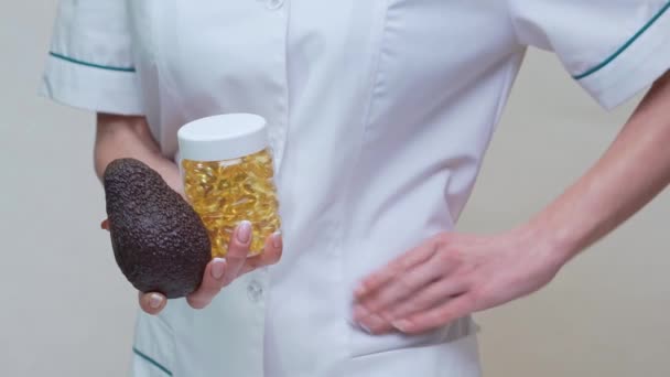 Nutriční lékař drží organické avokádo ovoce a sklenice medicíny nebo vitamin nebo omega 3 kapsle — Stock video