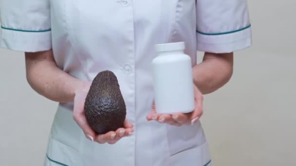 Táplálkozási orvos gazdaság szerves avokádó gyümölcs és üveg gyógyszer vagy vitamin vagy omega 3 kapszula — Stock videók