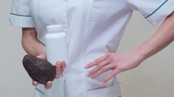 Medico nutrizionista in possesso di frutta biologica avocado e barattolo di medicina o vitamina o omega 3 capsule — Video Stock