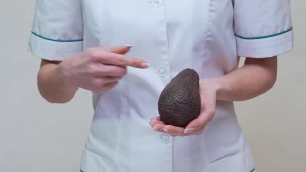 Nutricionista médico segurando frutas e medicamentos orgânicos abacate ou vitaminas ou ómega 3 cápsulas — Vídeo de Stock