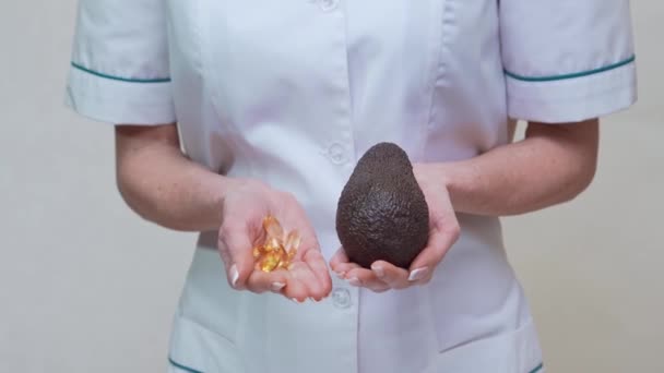 Nutritionniste médecin tenant des fruits d'avocat bio et de la médecine ou de la vitamine ou des oméga 3 capsules — Video