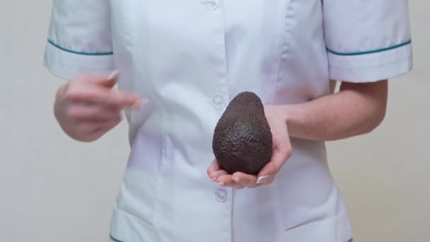 Nutricionista médico segurando frutas e medicamentos orgânicos abacate ou vitaminas ou ómega 3 cápsulas — Vídeo de Stock