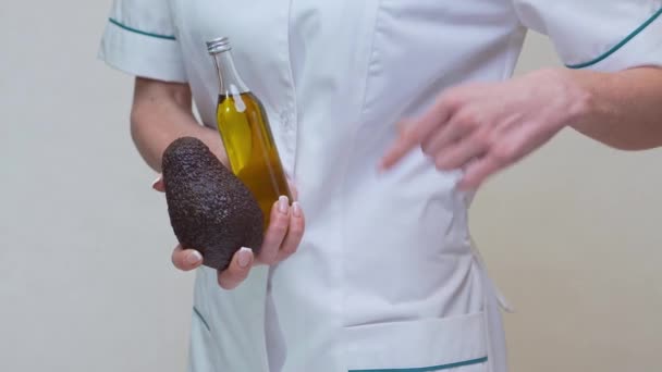 Врач-диетолог с органическими фруктами авокадо и бутылкой масла — стоковое видео