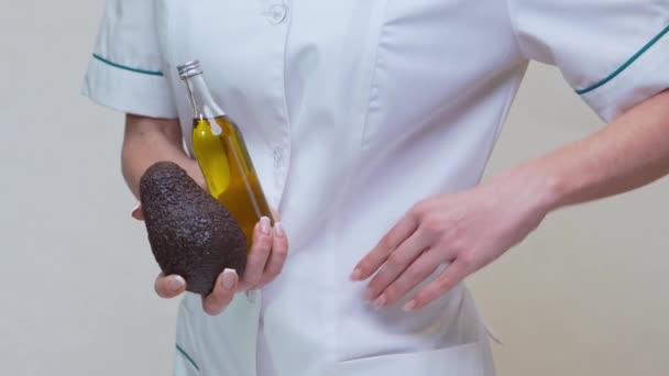 Voedingsdeskundige met biologisch avocado fruit en een fles olie — Stockvideo