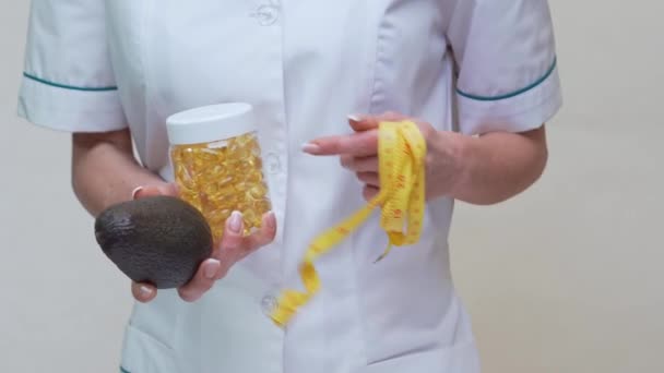 Nutricionista médico segurando frutas abacate orgânicos e frasco de remédio ou vitamina ou ômega 3 cápsulas — Vídeo de Stock