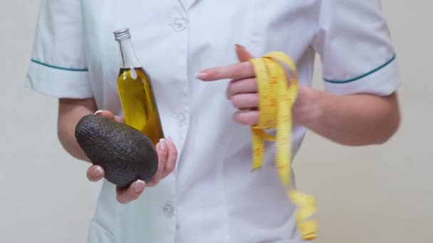 Nutricionista médico segurando frutas abacate orgânicos e garrafa de óleo — Vídeo de Stock