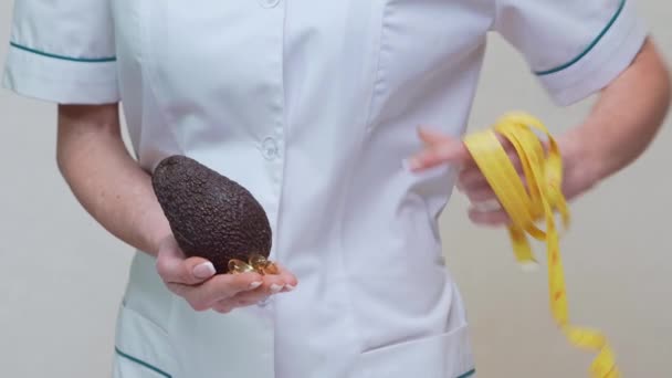 Nutricionista médico conceito de estilo de vida saudável - segurando frutas abacate orgânicos e fita métrica — Vídeo de Stock