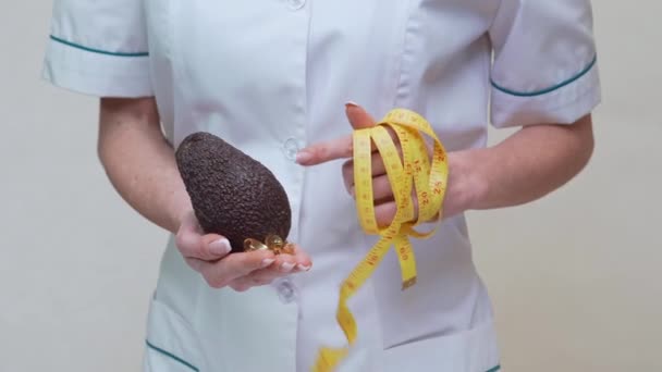 Nutricionista médico conceito de estilo de vida saudável - segurando frutas abacate orgânicos e fita métrica — Vídeo de Stock