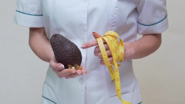 Nutricionista médico conceito de estilo de vida saudável - segurando frutas abacate orgânicos e fita métrica — Vídeo de Stock