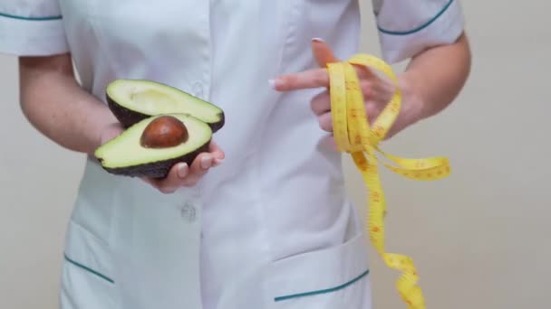 Nutricionista médico conceito de estilo de vida saudável - segurando frutas abacate orgânicos e fita métrica — Vídeo de Stock