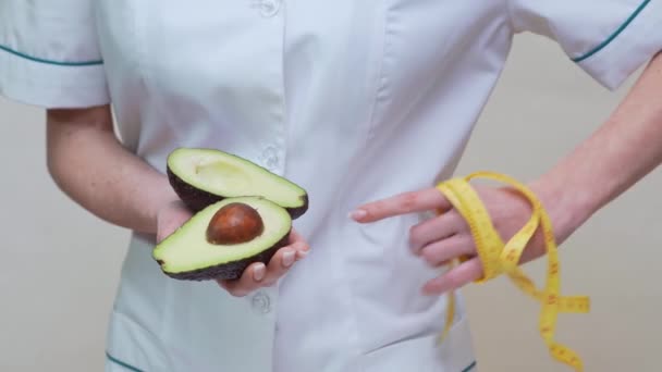 Nutricionista médico conceito de estilo de vida saudável - segurando frutas abacate orgânicos e fita métrica — Vídeo de Stock