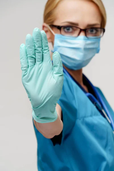 Médico enfermera mujer con estetoscopio con máscara protectora y guantes de goma o látex —  Fotos de Stock