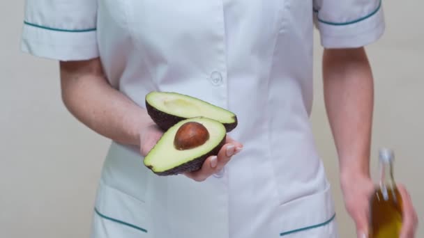 Διατροφολόγος γιατρός κρατώντας βιολογικά φρούτα αβοκάντο και μπουκάλι λάδι — Αρχείο Βίντεο