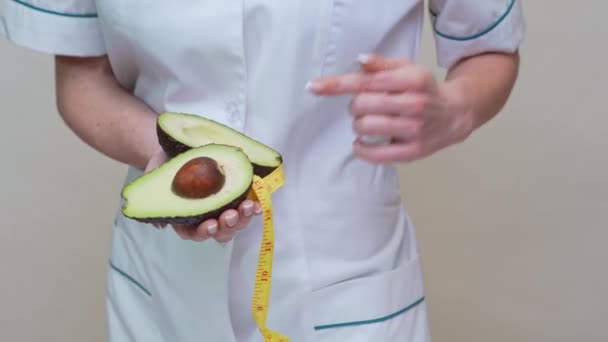 Dietetyk lekarz zdrowy styl życia koncepcja - gospodarstwa organiczne owoce awokado i taśma pomiarowa — Wideo stockowe