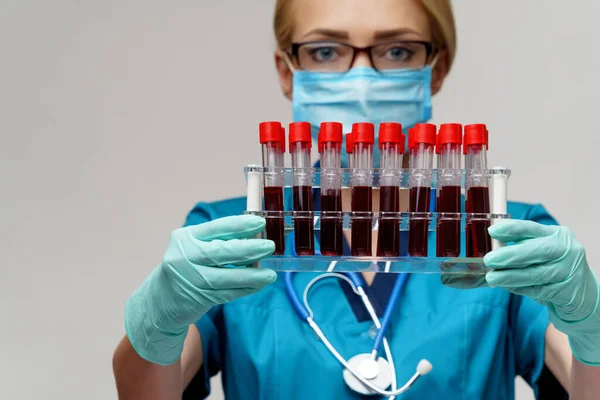 Médico enfermeira mulher usando máscara protetora e luvas - segurando rack com testes de sangue de vírus — Fotografia de Stock