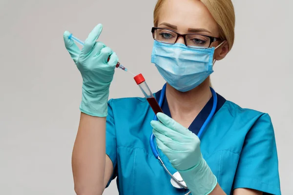 Verpleegkundige vrouw met beschermend masker en handschoenen - met virusreageerbuis en spuit — Stockfoto