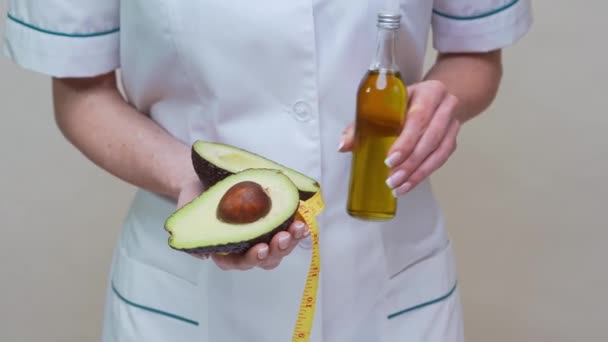 Nutritionist läkare som håller ekologisk avokado frukt och flaska olja — Stockvideo