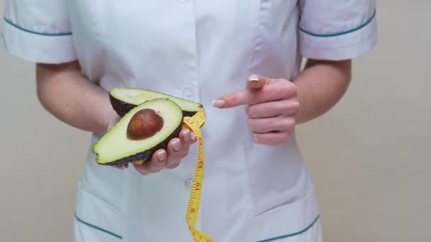 Nutritionist doctor healthy lifestyle concept - holding organic avocado fruit and measuring tape — Stock Video