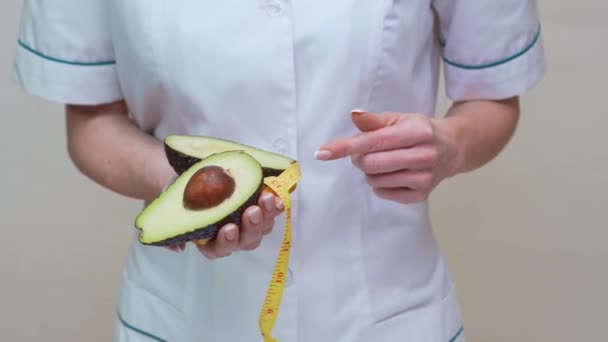 Nutritionist doctor healthy lifestyle concept - holding organic avocado fruit and measuring tape — Stock Video