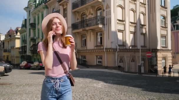 Чудова молода жінка туристка з кавою в центрі міста говорить по телефону. — стокове відео